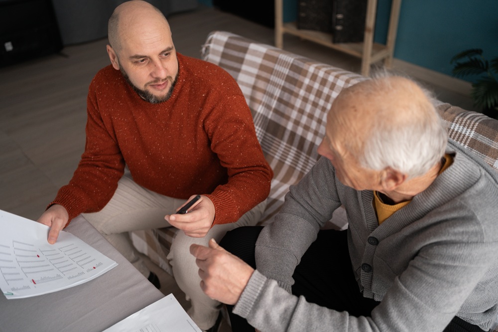 Homeowners Discussing Budget and Project Plans Together – New Construction Guidance Two men reviewing documents and financial details while planning home build with new construction guidance – New Construction Guidance