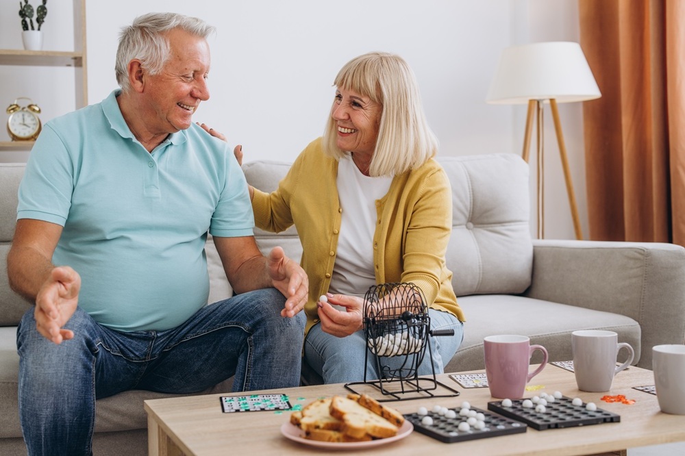 Happy Couple Discussing Future Home Plans Together – New Construction Guidance Older couple sitting on couch smiling and talking, representing planning support through new construction guidance – New Construction Guidance