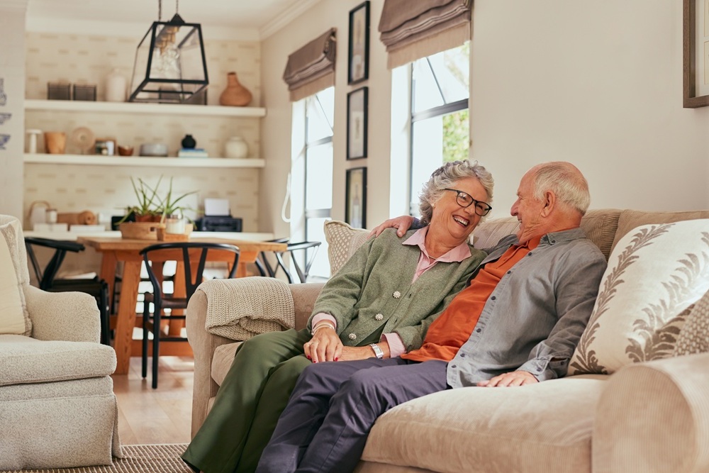Elderly couple sitting comfortably on couch in updated living room showcasing home remodeling consulting results – Home Remodeling Consulting